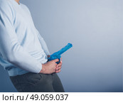 A young man is posing with a water pistol and is holding it in front of his crotch. Стоковое фото, агентство Ingram Publishing / Фотобанк Лори