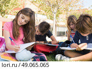 Group of little students sitting on the grass at school. Стоковое фото, агентство Ingram Publishing / Фотобанк Лори