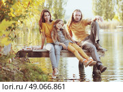 Happy family sitting by the lake. Стоковое фото, агентство Ingram Publishing / Фотобанк Лори