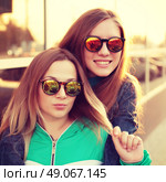 Close up fashion portrait of two young hipster girl friends, wearing mirrored sunglasses, having blonde and ombre hairs. Стоковое фото, агентство Ingram Publishing / Фотобанк Лори