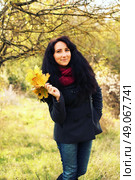 Excited happy fall woman smiling joyful and blissful holding autumn leaves outside in colorful fall forest. Young woman in beautiful autumn park, concept autumn. Стоковое фото, агентство Ingram Publishing / Фотобанк Лори