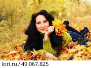 Excited happy fall woman smiling joyful and blissful holding autumn leaves outside in colorful fall forest. Young woman in beautiful autumn park, concept autumn. Стоковое фото, агентство Ingram Publishing / Фотобанк Лори