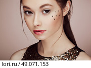 Portrait of beautiful young woman in a shiny golden dress. Brunette girl. Perfect make-up. Freckles. Стоковое фото, агентство Ingram Publishing / Фотобанк Лори