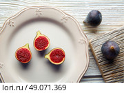 figs raw cutted fig fruits on white plate and wooden table. Стоковое фото, агентство Ingram Publishing / Фотобанк Лори