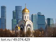 Вид на церковь и небоскрёбы. Современный городской пейзаж. Красивая церковь на фоне высотных зданий. Архитектурные достопримечательности Москвы. Церковь Георгия Победоносца, Поклонная гора, Москва, Россия. (2023 год). Редакционное фото, фотограф Андрей Степанов / Фотобанк Лори