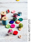 Threads and a set of buttons and bobbin on a bright light background. Working inventory seamstresses. Стоковое фото, агентство Ingram Publishing / Фотобанк Лори