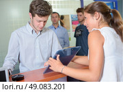 Lady showing clipboard to young man. Стоковое фото, агентство Ingram Publishing / Фотобанк Лори