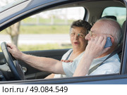 Elderly man on telephone while driving, wife in passenger seat. Стоковое фото, агентство Ingram Publishing / Фотобанк Лори