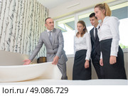 Man with hotel staff, holding bedspread. Стоковое фото, агентство Ingram Publishing / Фотобанк Лори