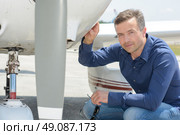 Portrait of man crouching by aircraft. Стоковое фото, агентство Ingram Publishing / Фотобанк Лори
