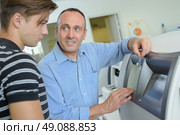 Man showing younger man how to use cash machine. Стоковое фото, агентство Ingram Publishing / Фотобанк Лори
