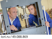 Two men looking at cylinder in vertical vice. Стоковое фото, агентство Ingram Publishing / Фотобанк Лори