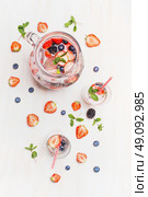 Summer drink with berries and ice cubes. Jug or Pitcher  with berries lemonade,Glasses  , straw and ingredients on  white wooden background, top view. Healthy vitamin drink. Стоковое фото, агентство Ingram Publishing / Фотобанк Лори