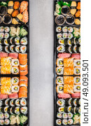Sushi sets assortment in bento boxes on gray stone background, top view, vertical border.  Japanese and Asian food. Стоковое фото, агентство Ingram Publishing / Фотобанк Лори