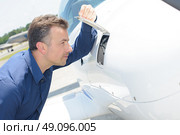 Man looking through open flap on aircraft. Стоковое фото, агентство Ingram Publishing / Фотобанк Лори