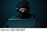 Мужчина в маске балаклаве и с гарнитурой за ноутбуком. Стоковое AI-изображение, AI-художник Илья Старков / Фотобанк Лори