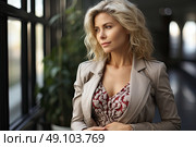 Poised woman in a chic taupe jacket and patterned top stands contemplatively in a softly lit atrium, exuding an aura of calm sophistication. Стоковое AI-изображение, AI-художник Данила Большаков / Фотобанк Лори