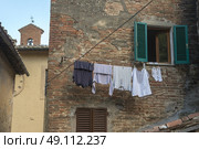 Low angle view of a clothesline hanging by wall, Montepulciano, Siena, Tuscany, Italy. Стоковое фото, агентство Ingram Publishing / Фотобанк Лори
