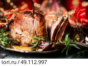 Christmas sliced roasted ham on dinning table with festive holiday decoration, side view,close up. Стоковое фото, агентство Ingram Publishing / Фотобанк Лори