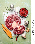 Veal shank slices meat and ingredients for Osso Buco cooking, composing on rustic wooden background, top view. Стоковое фото, агентство Ingram Publishing / Фотобанк Лори