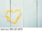Heart Shape Yellow Autumn Leaves On Turquoise Wood Table. Стоковое фото, агентство Ingram Publishing / Фотобанк Лори