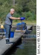 senior man feeding sturgeon fish in caviar farm. Стоковое фото, агентство Ingram Publishing / Фотобанк Лори