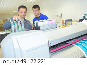 Man adjusting ink cartridges on professional printing machine. Стоковое фото, агентство Ingram Publishing / Фотобанк Лори