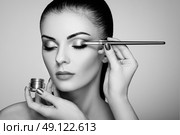 Makeup artist applies eye shadow. Beautiful woman face. Perfect makeup. Makeup detail. Beauty girl with perfect skin. Nails and manicure. Black and White. Стоковое фото, агентство Ingram Publishing / Фотобанк Лори