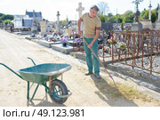 Man weeding around graves. Стоковое фото, агентство Ingram Publishing / Фотобанк Лори