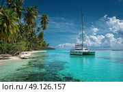 A sailboat is floating in the ocean near a beach. Стоковое AI-изображение, AI-художник Ярославский Максим / Фотобанк Лори