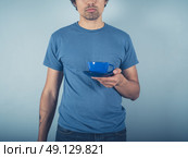 A young man wearing a blue t-shirt is holding a cup of cappucino. Стоковое фото, агентство Ingram Publishing / Фотобанк Лори