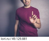 A young man in purple is raising his finger to swipe, push or establish authority. Стоковое фото, агентство Ingram Publishing / Фотобанк Лори