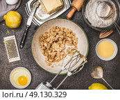 Lemon cookie or cake preparation with cooking ingredients. Butter and sugar mixing with hand mixer on dark kitchen table background , top view. Стоковое фото, агентство Ingram Publishing / Фотобанк Лори