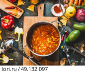 Mexican vegetarian  bean soup in cooking pot with ladle on rustic kitchen table ingredients and cutting board, top view. Vegan or vegetarian healthy food concept. Стоковое фото, агентство Ingram Publishing / Фотобанк Лори