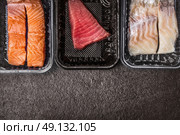 Selection of raw colorful fish fillets : salmon, tuna and codfish in plastic boxes on dark rustic background, top view, border, place for text. Healthy Seafood concept. Стоковое фото, агентство Ingram Publishing / Фотобанк Лори
