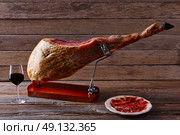 Iberian ham pata negra from Spain with red wine on wood background. Стоковое фото, агентство Ingram Publishing / Фотобанк Лори