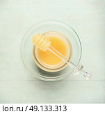 Glass jar with honey and dipper on light blue background, top view. Стоковое фото, агентство Ingram Publishing / Фотобанк Лори