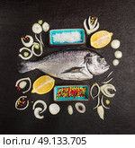 Composing with dorado raw fish, lemon and spices on black textured background , top view. Стоковое фото, агентство Ingram Publishing / Фотобанк Лори
