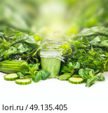 Smoothie in glass over green vegetables background on white table, frame. Стоковое фото, агентство Ingram Publishing / Фотобанк Лори