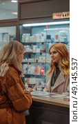 Two women are talking at the counter of a pharmacy. One is behind the counter, possibly an employee, and the other appears to be a customer. Стоковое AI-изображение, AI-художник Данила Большаков / Фотобанк Лори