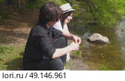 A young happy couple feeds ducks on the shore of a pond in a summer park. Стоковое видео, видеограф Ярославский Максим / Фотобанк Лори
