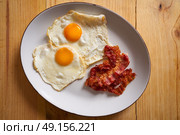 Breakfast bacon and eggs over easy on wood table. Стоковое фото, агентство Ingram Publishing / Фотобанк Лори