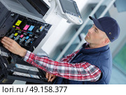 young man in cap working on offset printing machine. Стоковое фото, агентство Ingram Publishing / Фотобанк Лори