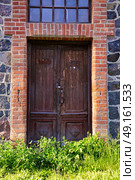 Neglect single wooden door in old city house. Old cast house wall with wooden door and window. Стоковое фото, агентство Ingram Publishing / Фотобанк Лори
