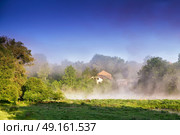 Misty morning on the river. Foggy River landscape through misty marshland on an early morning in spring. House and village in a fog. Стоковое фото, агентство Ingram Publishing / Фотобанк Лори