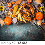 Roasted stuffed whole turkey or chicken with organic harvest vegetables ,pumpkin and corn ears for Thanksgiving dinner served on rustic table background with fall flowers arrangements, top view. Стоковое фото, агентство Ingram Publishing / Фотобанк Лори