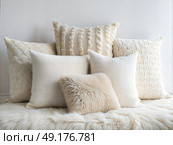 A delightful assortment of plush cushions in soft neutrals sits elegantly on a fluffy throw, enhancing the comfort and tranquility of the indoor space with layered textures. Стоковое AI-изображение, AI-художник Ольга Игнашина / Фотобанк Лори