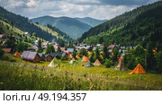 A cluster of tents pitched on a hillside, creating a makeshift camping site in the great outdoors. Стоковое AI-изображение, AI-художник Данила Большаков / Фотобанк Лори