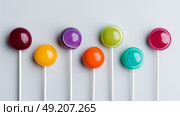 Minimalist background with colorful lollipops arranged symmetrically, flat lay. Стоковое AI-изображение, AI-художник ALLA YURTAYEVA / Фотобанк Лори