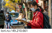 A woman wearing a face mask sits engrossed in a book, showcasing the new normal of reading during the pandemic. Стоковое AI-изображение, AI-художник Данила Большаков / Фотобанк Лори